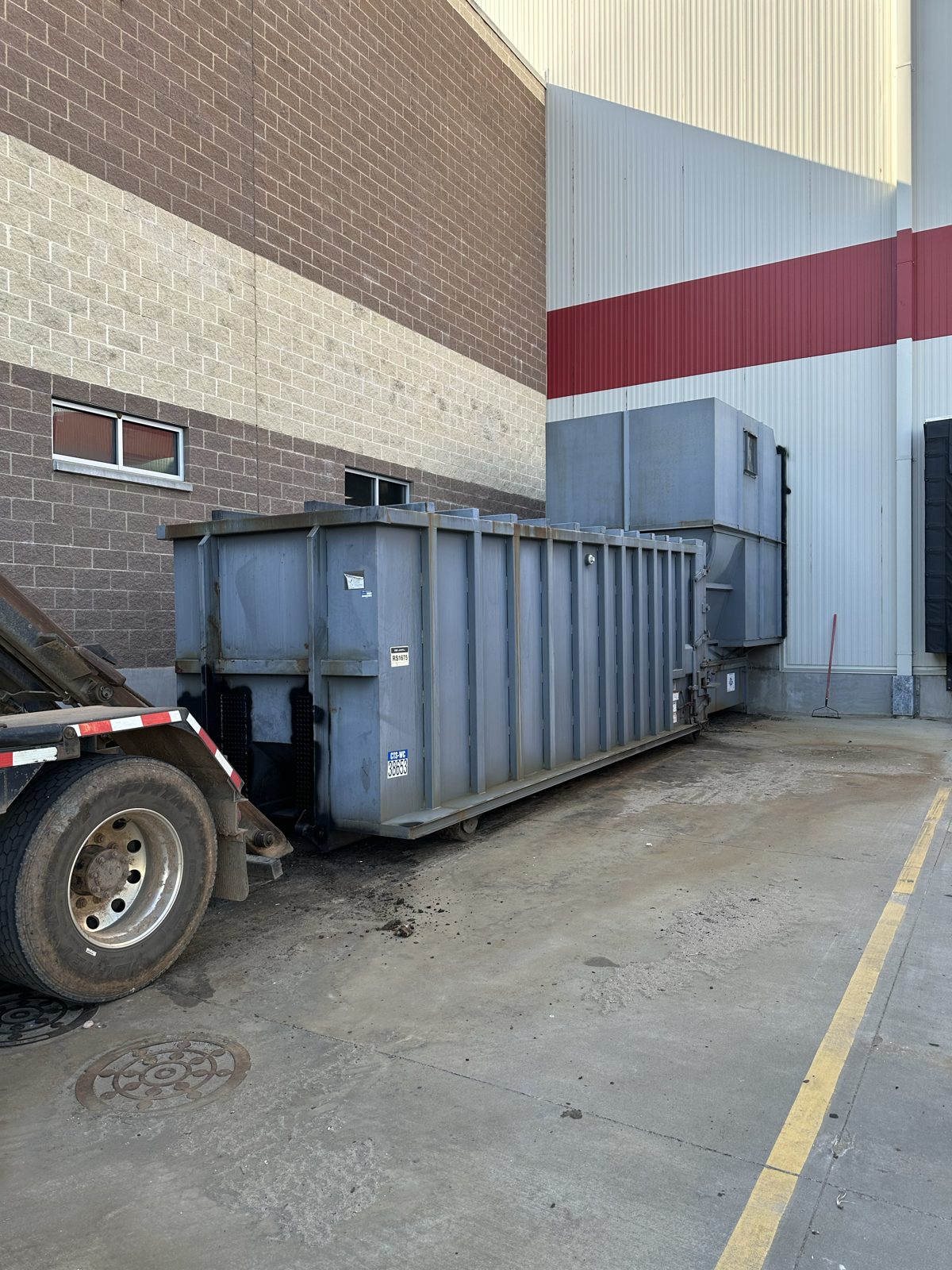 Commercial waste compactor installed behind a retail building