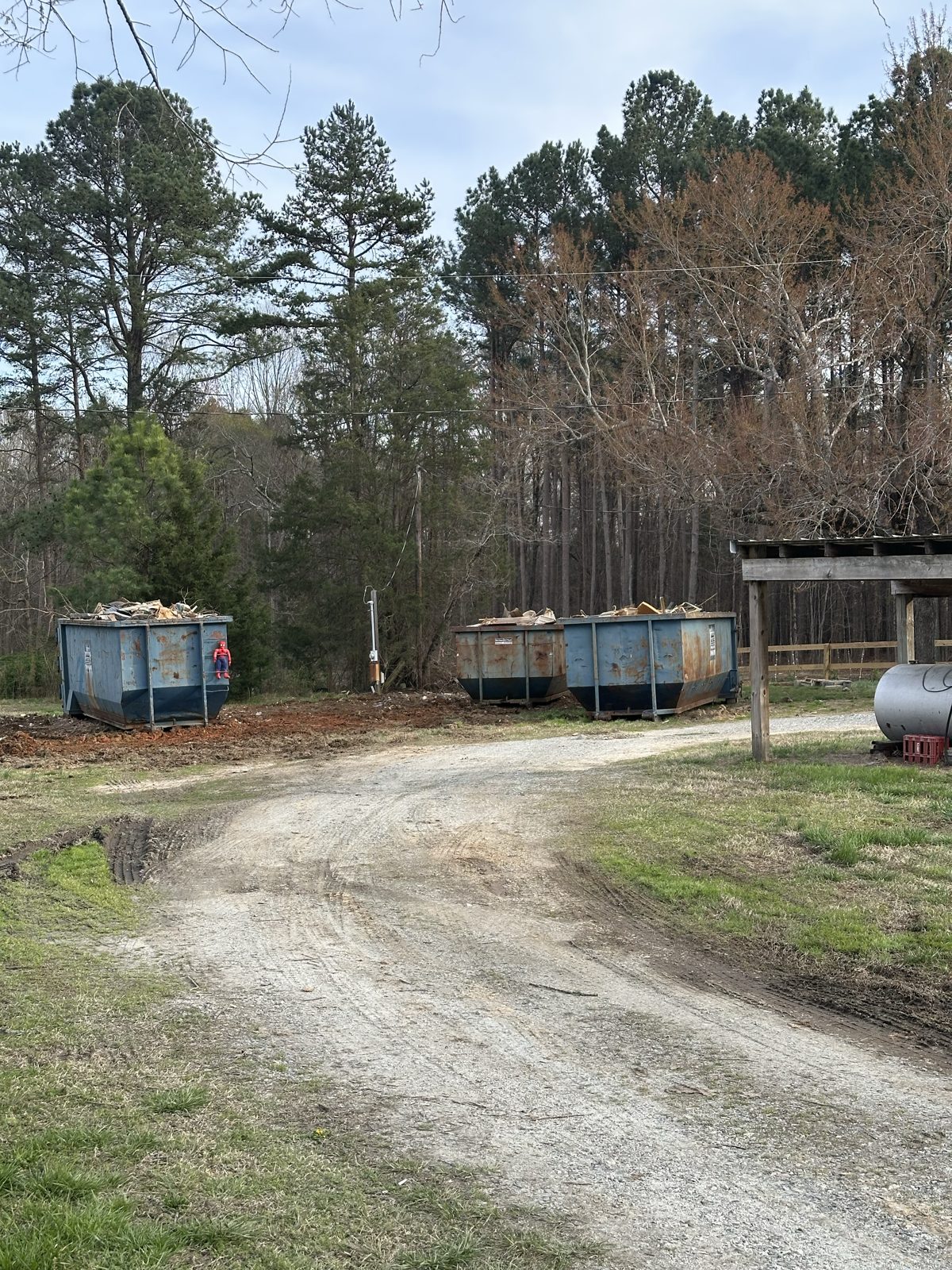 Cleared driveway with three loaded dumpsters after demolition