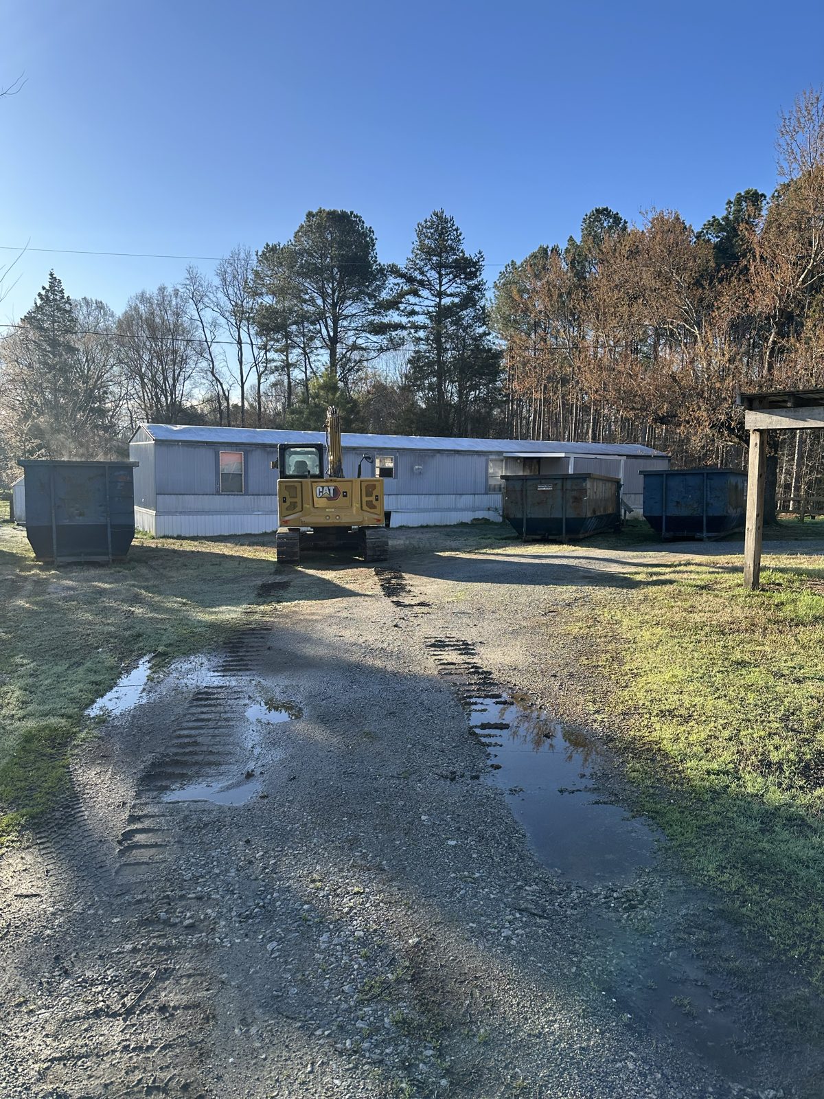 Mobile home with excavator and dumpsters staged before demolition