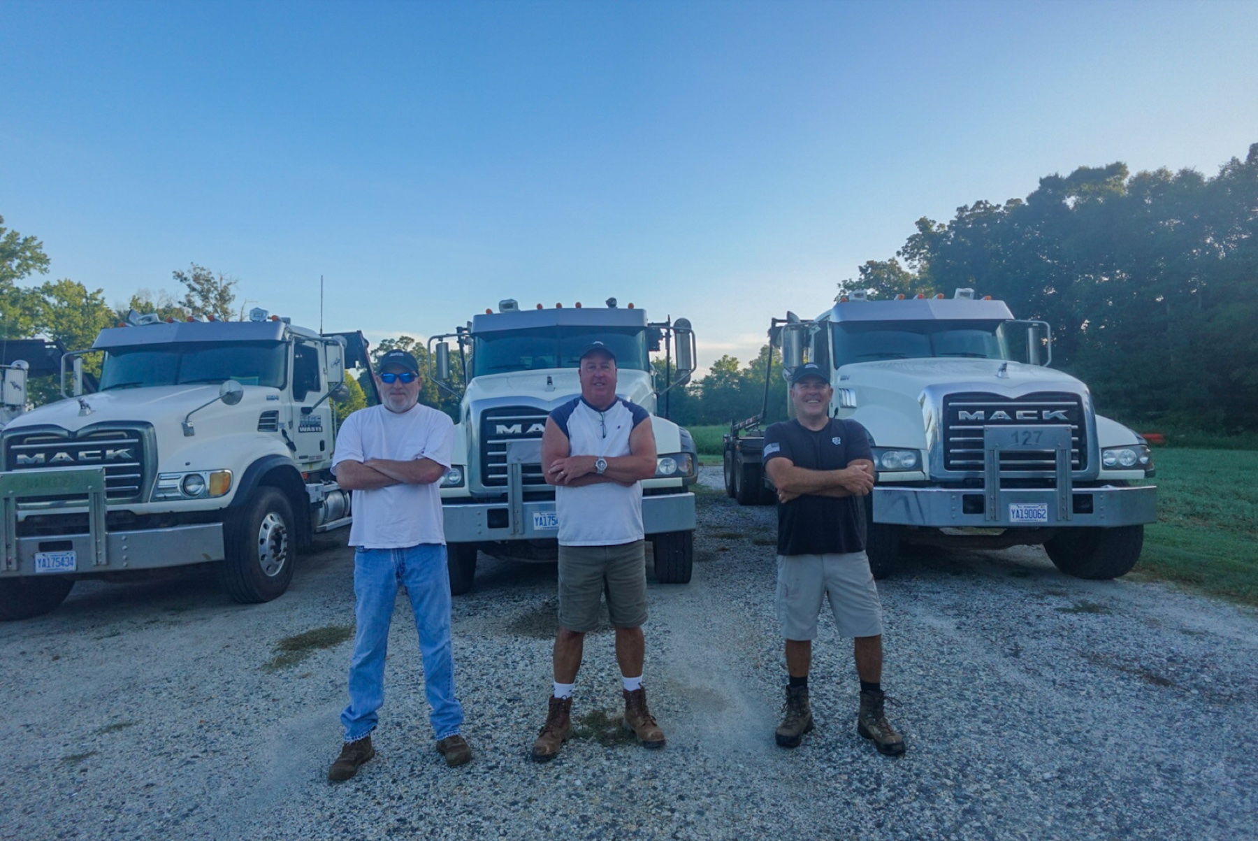 Martin, Gerald, and Chad standing in front of the MGS Waste truck fleet